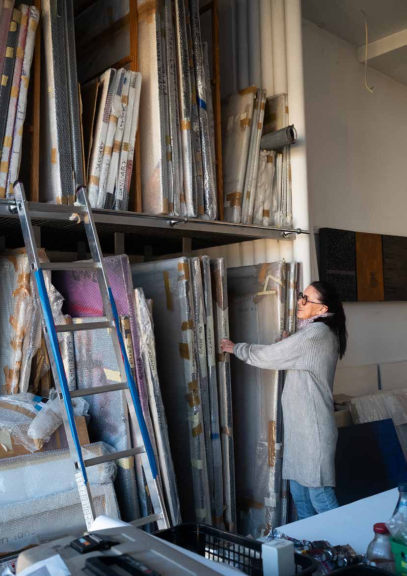 Hanna Zawa-Cywińska in her studio among stacked canvases